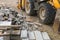 Stack of concrete paving stones with tractor background. Repair pavement and laying paving slabs on walkway. Building materials