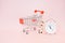 Stack of contact us icon on wood cubes, white analog alarm clock and blurred shopping cart on sweet pink background