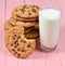 Stack of cookies with chocolate, glass of yogurt on a pink wooden