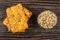 Stack of cookies with sunflower seeds and bowl with peeled seeds on dark wooden table. Top view