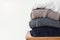 Stack of cozy winter sweaters on the white wall background.