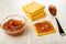 Stack of crackers, bowl with apple jam, spoon, sandwich from cookie with jam on table