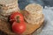 Stack of crispbread, tomatoes and raw buckwheat on wooden piece