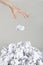 Stack of crumpled paper balls and hand on gray