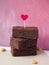 A stack of delicious brownie pieces decorated with a topper in the shape of a heart.