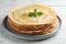 Stack of delicious crepes with mint and melting butter on white wooden table, closeup