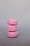 Stack of delicious french pink strawberry macarons on grey background. Tasty colorful sandwich cookies