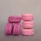 Stack of delicious french raspberry and blueberry flavour macarons on grey background