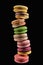 Stack of delicious fresh French macaroons of different flavors isolated on black.