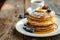 Stack of delicious pancakes topped with butter and honey, served on a white plate on a wooden table