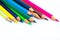 Stack of different colored wood pencil crayons scattered across a white background