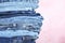 Stack of different jeans on pink background