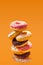 Stack of donuts on orange background including chocolate frosting, topping, coconut and frosting