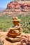 Stack of flat red rocks with a large multicolored red outcropping in the distance with trees