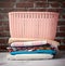 Stack of folded laundry and empty laundry basket, brown brick wall background