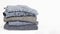 Stack of folded woolen knitwear on white background. Season of warm knitted clothes: sweaters, jumpers, cardigans