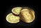 Stack of four golden Bitcoins laying on the black background.