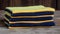 a stack of four towels sitting on top of a wooden table next to a wooden tablecloth covered in a blue and yellow stripe pattern