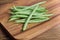 Stack of fresh needle beans on wooden cutting board