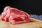 Stack of fresh raw lamb loin chops on a wooden board and white and blue table cloth,