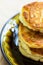 Stack of freshly fried homemade fluffy pancakes from cottage cheese on dark plate on wooden kitchen table. Appetizing golden crust