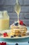 A stack of freshly prepared pancakes is poured with condensed milk. Tasty breakfast with fresh berries