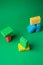 Stack geometric blocks construction abstract sponges in red, yellow, blue colors, on green paper background, copy space