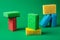 Stack geometric blocks construction abstract sponges in red, yellow, blue colors, on green paper background, copy space