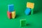 Stack geometric blocks construction abstract sponges in red, yellow, blue colors, on green paper background, copy space