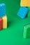 Stack geometric blocks construction abstract sponges in red, yellow, blue colors, on green paper background, copy space