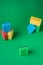 Stack geometric blocks construction abstract sponges in red, yellow, blue colors, on green paper background, copy space