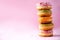 Stack of glazed colorful assorted donuts with sprinkles on pink background. Copy space. Sweet doughnuts for kids