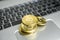 A stack of golden bitcoin coin on a silver keyboard of laptop. Virtual cryptocurrency concept. Mining of bitcoins online