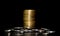 Stack of golden coins and heap of silver coins on a black background