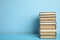 Stack of hardcover books on blue background, space for text