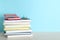 Stack of hardcover books and calculator on table against color background