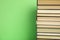 Stack of hardcover books on green background. Space for text