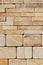 A stack of hewn, rounded yellow sandstone stones in the lower half and rough rectangular tiles at the top