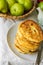 Stack of homemade mascarpone pancakes fritters on plate on white cotton tablecloth pears in wicker basket. Breakfast setting