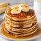 Stack of homemade pancakes with banana and maple syrup, selective focus.