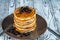 Stack of homemade pancakes with berries and honey on brown plate on rustic background