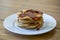 Stack of homemade plain American style pancakes with golden syrup poured over them on wooden table