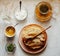 Stack of hot classic Russian thin pancakes. Rustic style. Sour cream, butter, greenery, honey, eggs and tea pot are near