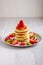 Stack of hot flapjacks served with fresh strawberries and kiwi on white wooden table
