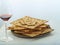 A stack of Jewish bread matzah and a glass with red wine on a white background. Jewish Passover, a traditional Jewish holiday