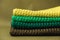 Stack of knitted material from threads of yellow, green, brown colors on a green background. Copy, empty space for text