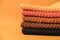 Stack of knitted material from threads of yellow, orange, brown colors on a orange background. Copy, empty space for text