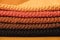 Stack of knitted material from threads of yellow, orange, brown colors on a orange background. Copy, empty space for text