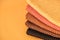 Stack of knitted material from threads of yellow, orange, brown colors on a orange background. Top view. Copy, empty space for