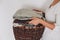 Stack of knitted sweaters on wicker basket in young female hands